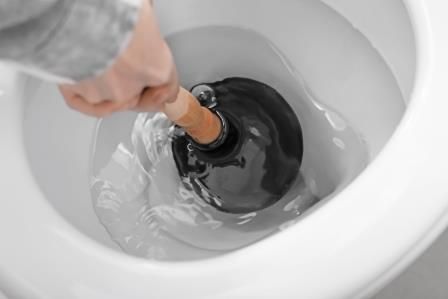 Vancouver plumber unclogging a toilet