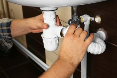 An emergency plumber unclogging a sink drain in Vancouver